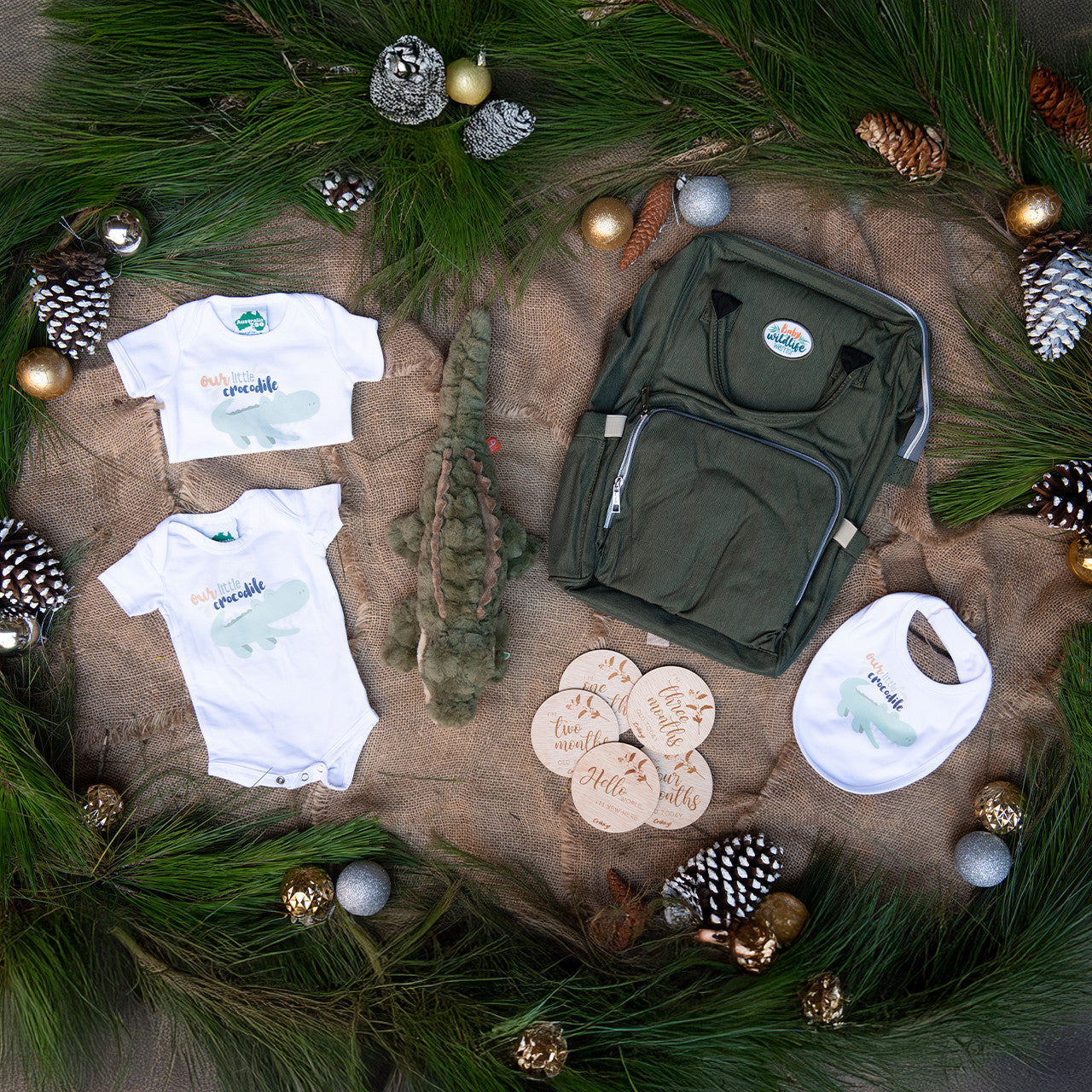 Australia Zoo baby clothing and accessories on a textured surface with greenery and ornaments.