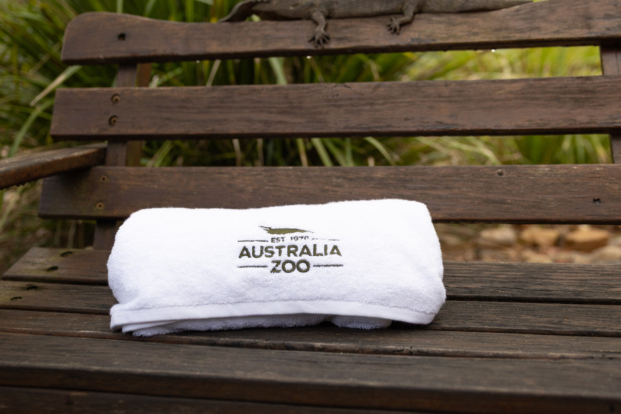 White towel with 'Australia Zoo' logo on a wooden bench