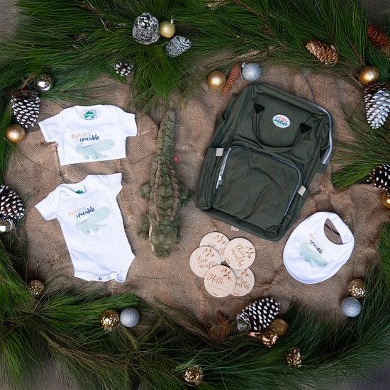 Australia Zoo baby clothing and accessories on a textured surface with greenery and ornaments.